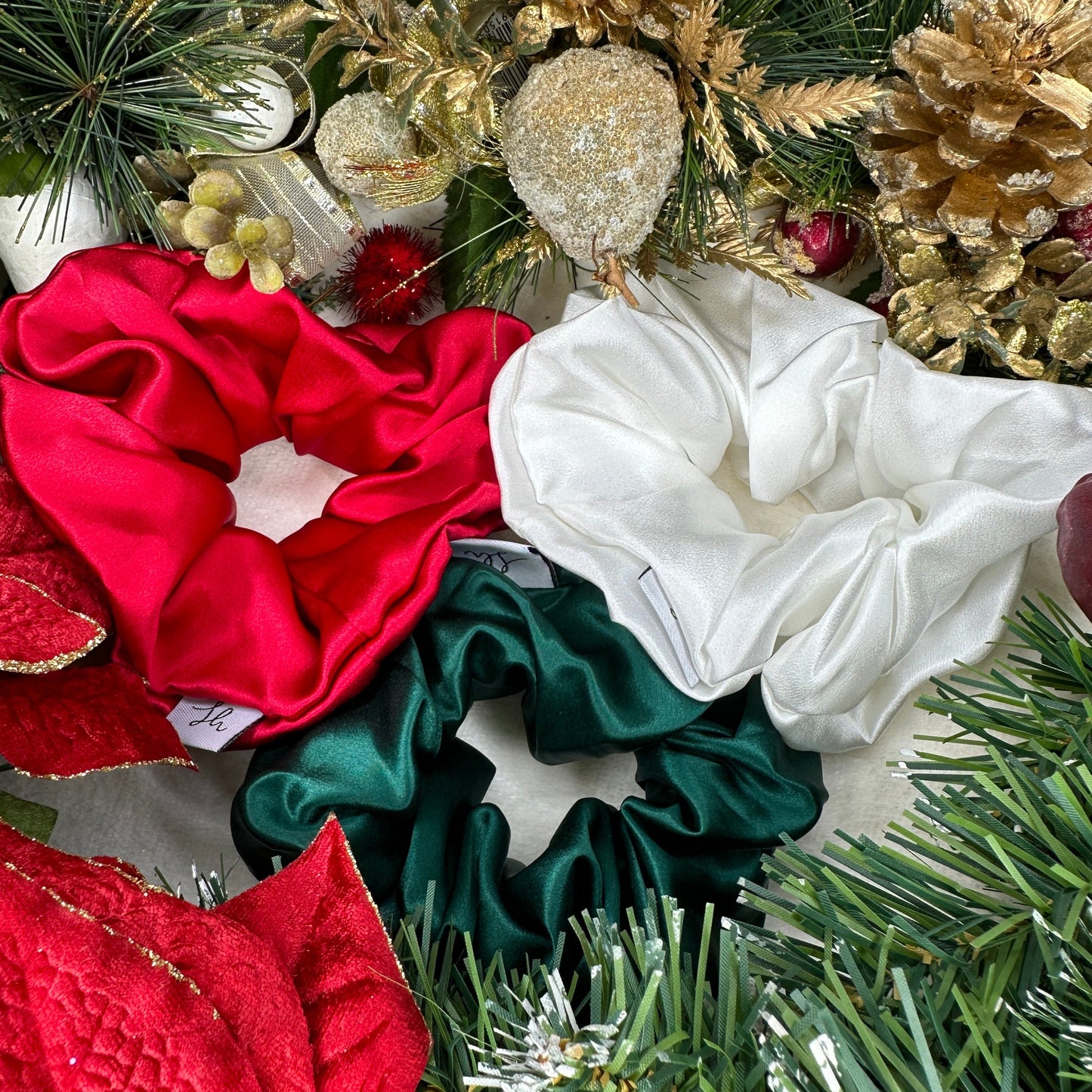 Sioda Hair Silky Range, The Christmas Collection 100% Mulberry Silk scrunchies in white, green and red set against a white powder effect surrounded by a christmas wreath, size large