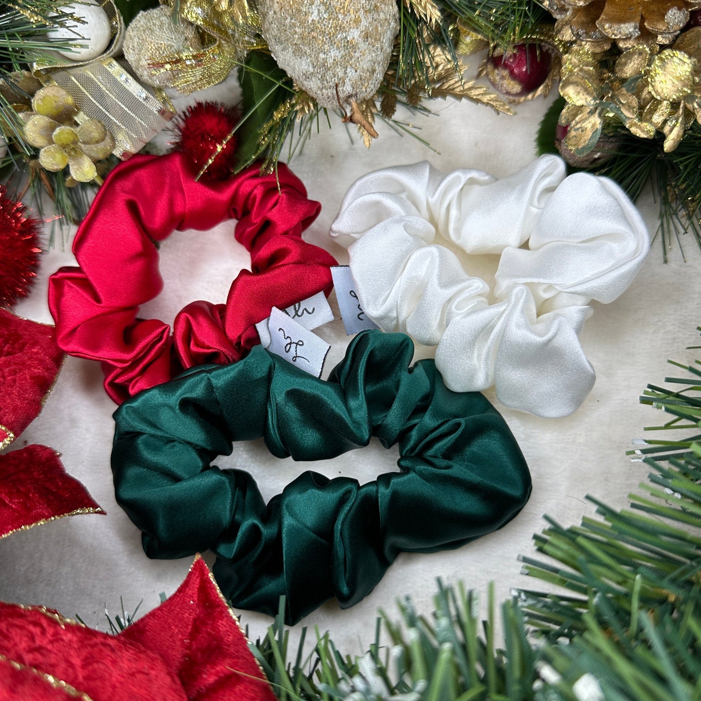 Sioda Hair Silky Range, The Christmas Collection 100% Mulberry Silk scrunchies in white, green and red set against a white powder effect surrounded by a christmas wreath, size medium