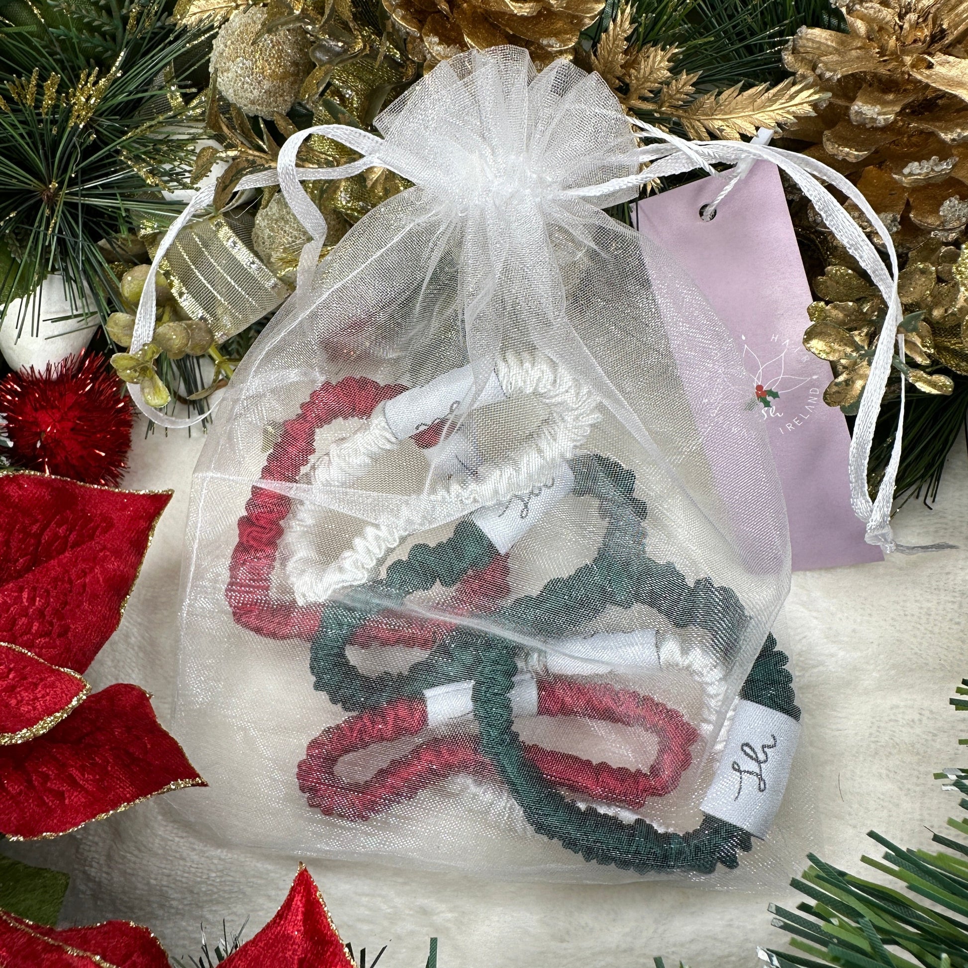 Sioda Hair Silky Range, The Christmas Collection 100% Mulberry Silk scrunchies in white, green and red set against a white powder effect surrounded by a christmas wreath, size small, in a white net pouch