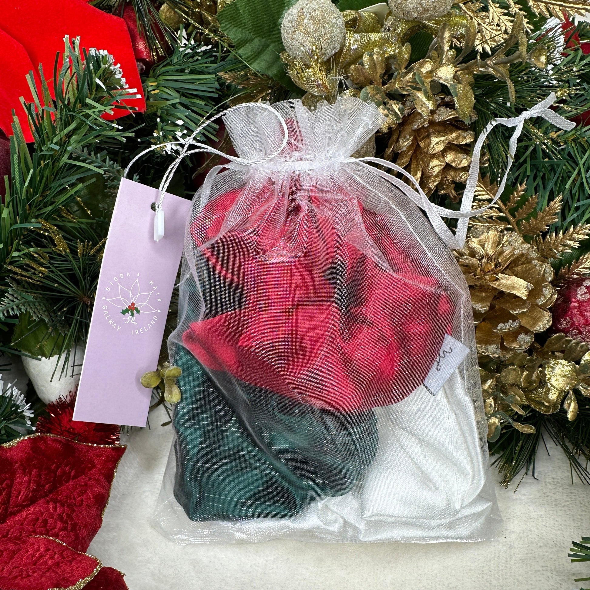 Sioda Hair Silky Range, The Christmas Collection 100% Mulberry Silk scrunchies in white, green and red set against a white powder effect surrounded by a christmas wreath, size large, packaged in a white net pouch